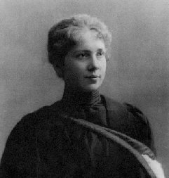Fotografía de Emmy Noether de pie junto a una silla.